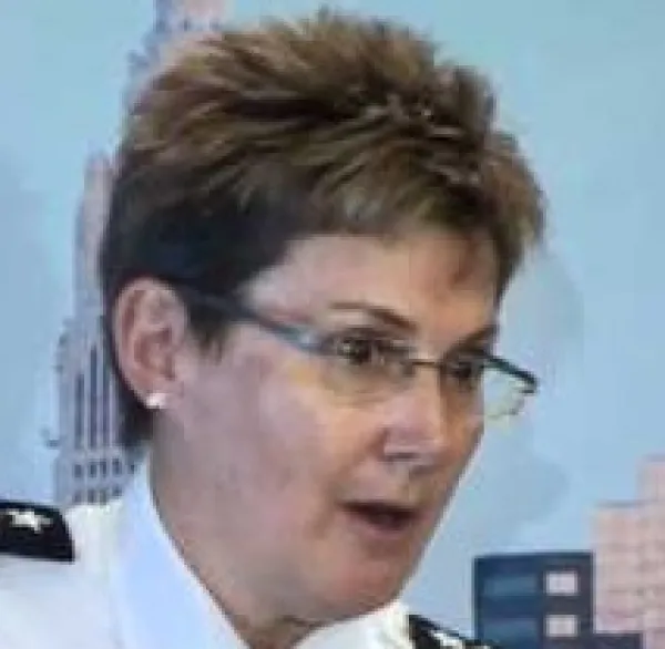 White women with glasses and short brown hair wearing a police uniform looking surprised