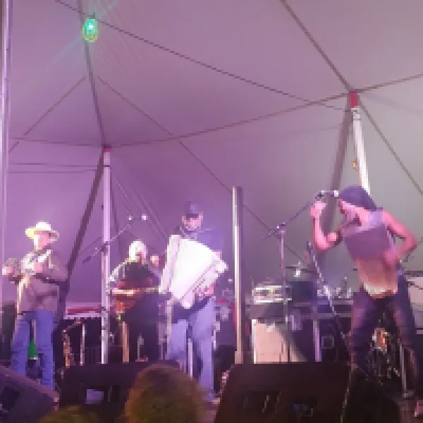 Three musicians on a stage, one playing an accordion