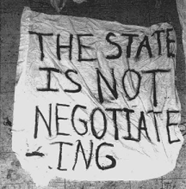 A crudely hand lettered sign on what looks like a sheet saying The state is not negotiating