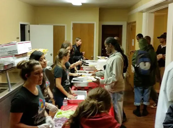 People serving food at a long table