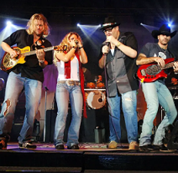 Four guy onstage playing guitars, harmonica and singing wearing cowboy type of clothes