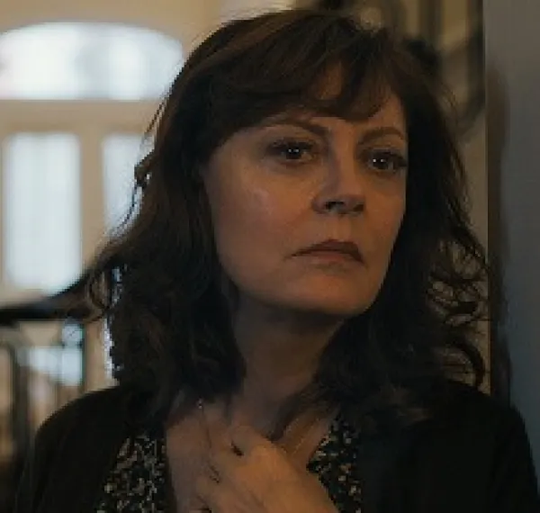 White woman with long curly brown hair looking pensive