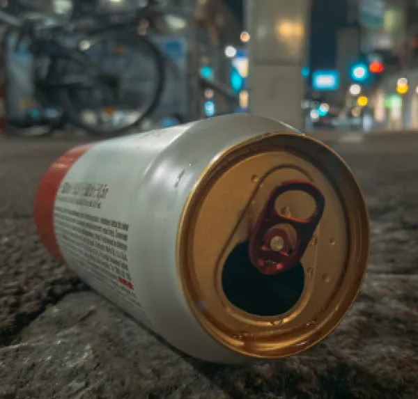 Empty beer can on the ground outside at night