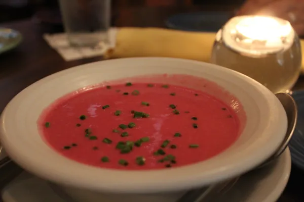 White bowl with red soup and green chives sprinkled on top