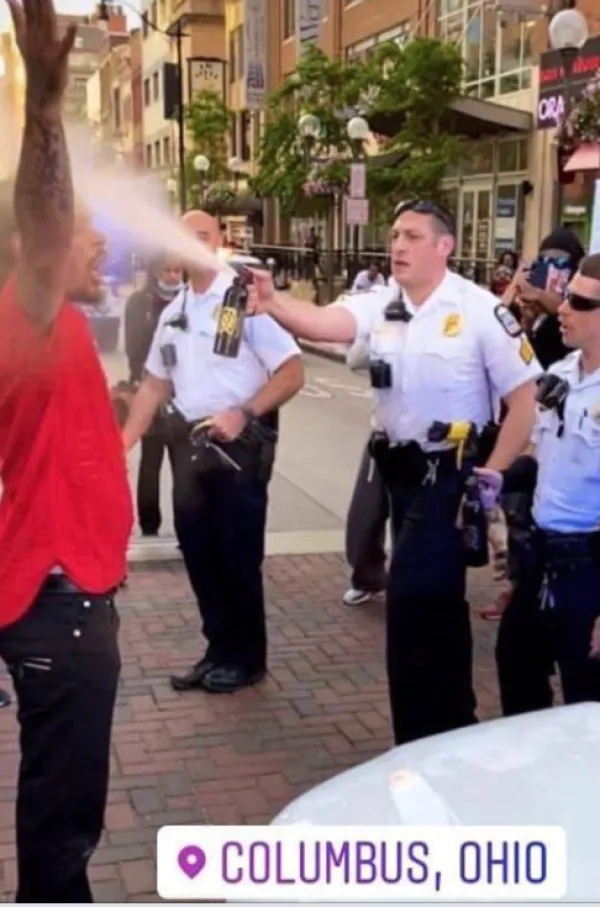 Cop spraying black man with hands in air