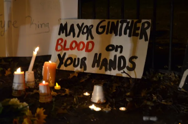 Candles and a sign that says "Mayor Ginther Blood on your hands"