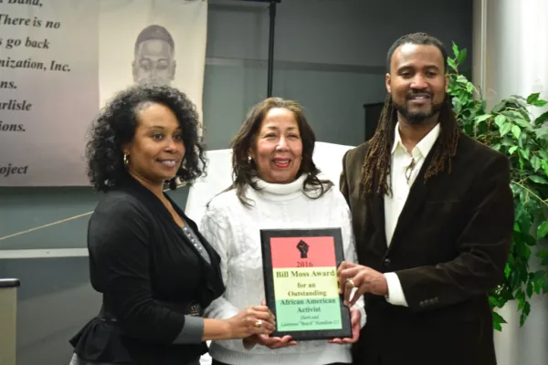 Sherri and Butch posing on each side of Ruth Moss holding award