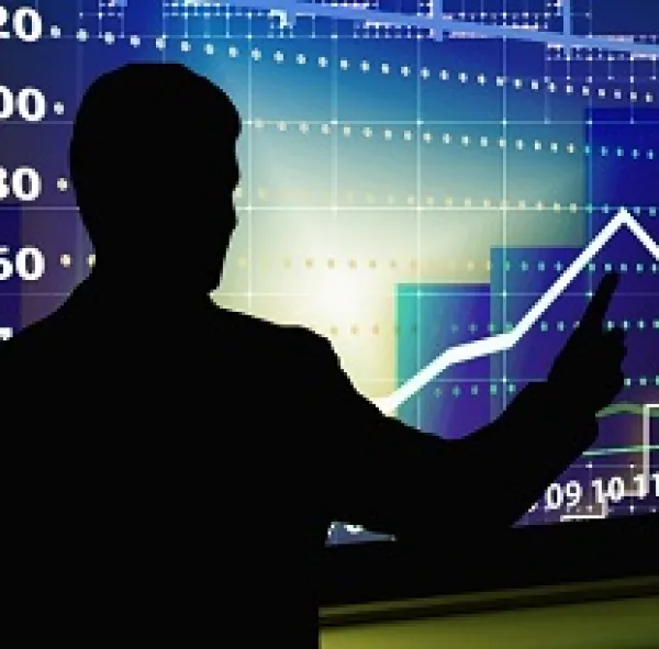 Black silhouette of the back of a man pointing to a bright blue graph that shows a line going up and down