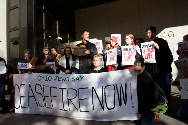 People outside with banner reading ceasefire now