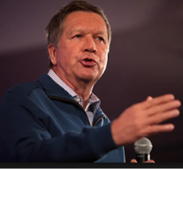 Older white man gesturing as he speaks holding a mic