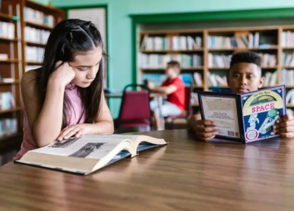 Kids reading at table in library