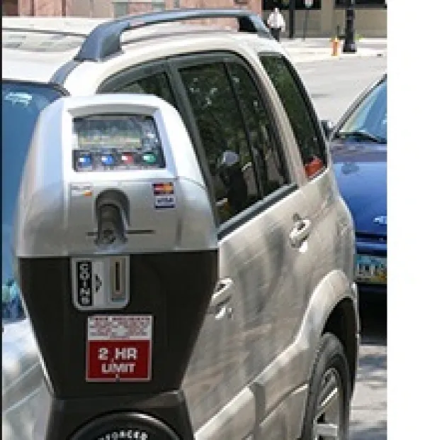 Close up of a parking meter and cars parked behind it
