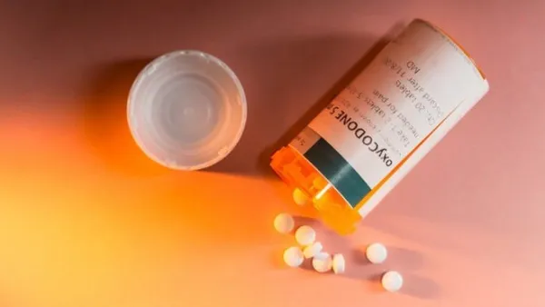 A pill bottle with white pills spilling out