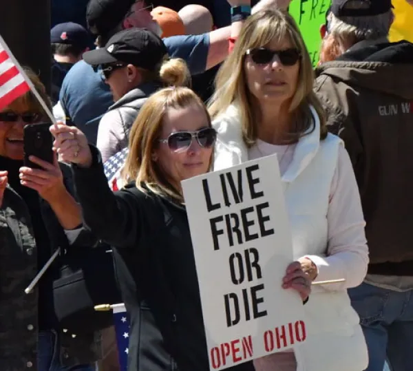 Woman holding sign saying Live Free or Die