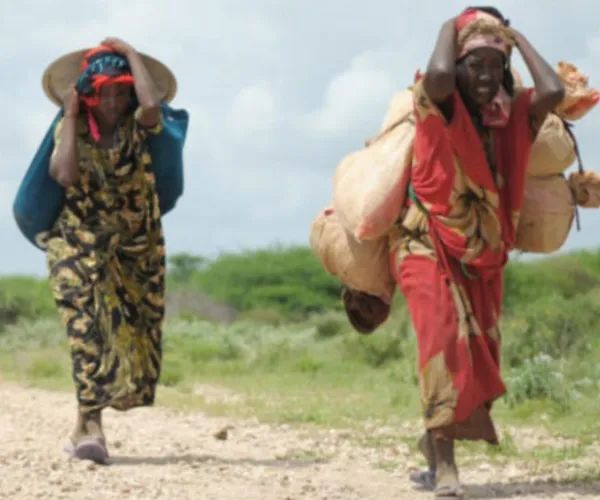 Immigrant women walking on dirt path in Africa