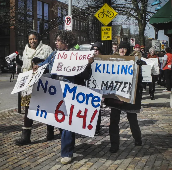 People marching down High Street holding signs that say No More in 614, no more bigotry, black lives matter.