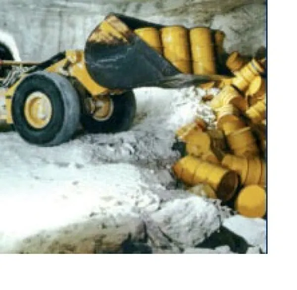 Bulldozer pushing yellow barrels into a ditch