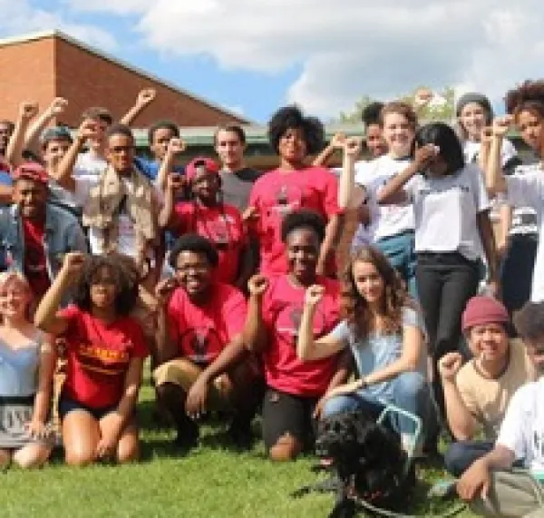 Young people posing outside wearing mostly red shirts with their fists in the air
