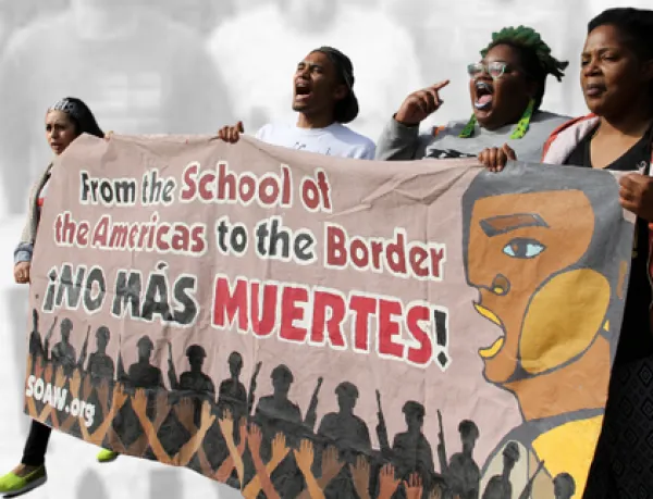 Women holding banner about closing SOA and yelling