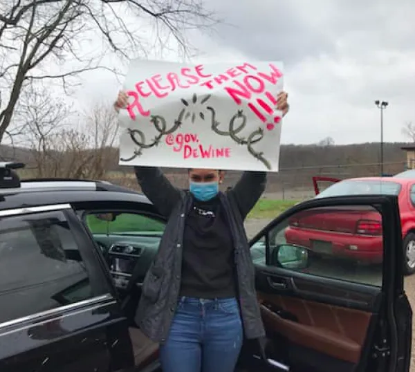 Woman holding a sign saying Release Them Now