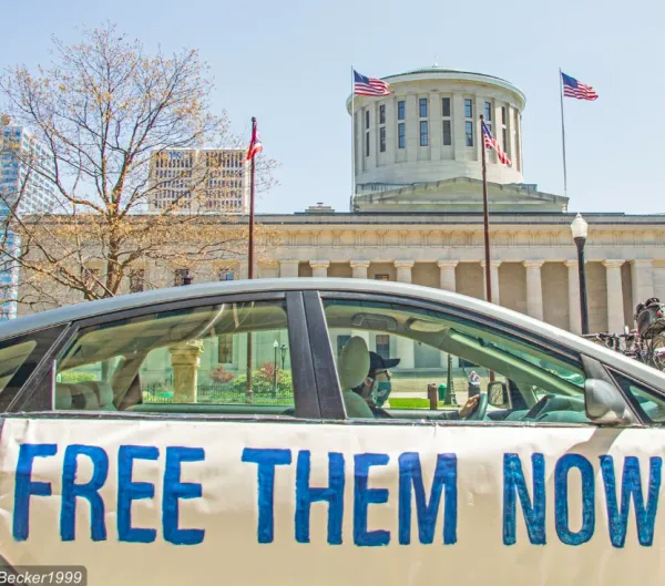 Car with sign saying Free Them Now in front of Ohio Statehouse