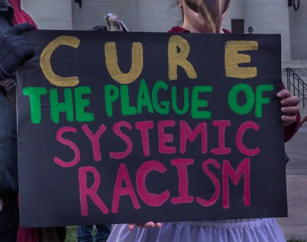 Sign saying Cure the Plague of Systemic Racism