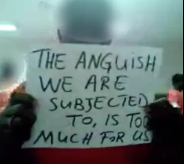 An inmate holding a sign saying The Anguish we are subjected to is too much for us