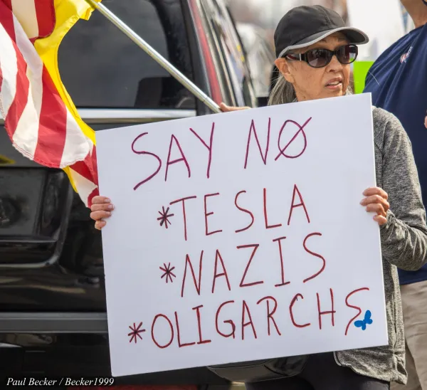 Woman holding sign at Tesla protest