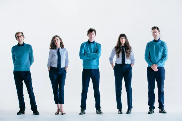 Four white people standing in a row dressed the same