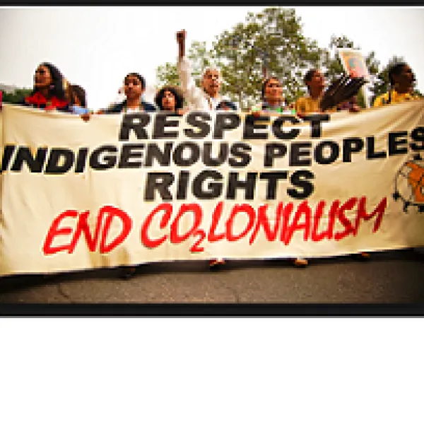 People marching outside with a huge banner that reads Respect Indigenous People's Rights End colonialism
